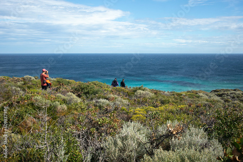 a man walking into the bushes od western Australia with the turquoise Indian ocean.