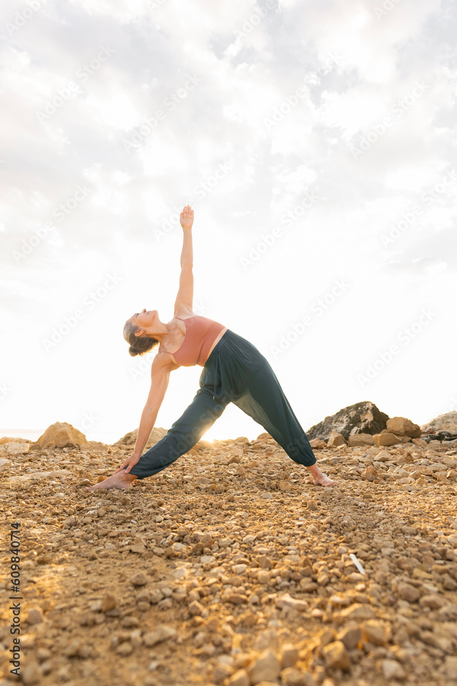 Woman doing Half Moon pose at beach Woman doing Half Moon pose at beach