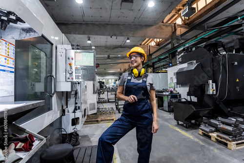Smiling maintenance engineer standing by CNC machine in modern factory photo