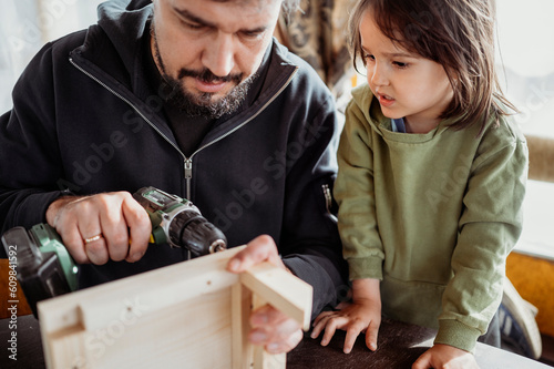 Boy with father building up birdhouse at home photo