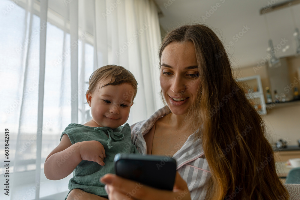 Mother showing smart phone to baby girl at home Mother showing smart phone to baby girl at home