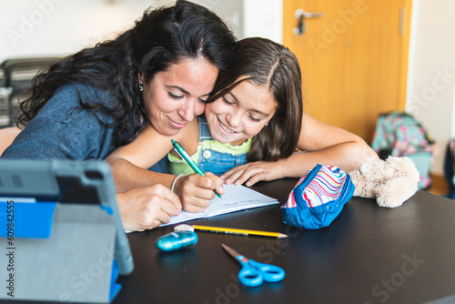 Mother homeschooling daughter at home photo