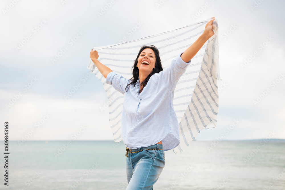 Carefree woman with scarf laughing at beach Carefree woman with scarf laughing at beach