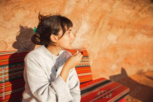 Thoughtful young woman with cup of tea in majlis