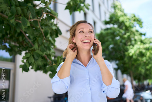 Happy woman with hand in hair talking on smart phone photo
