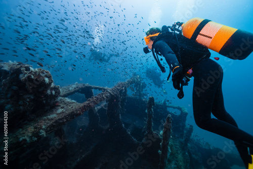 Men and woman scuba diving and examining sunken ship El Naranjito undersea