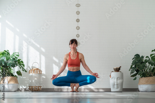 Woman practicing Lotus position in front of wall photo