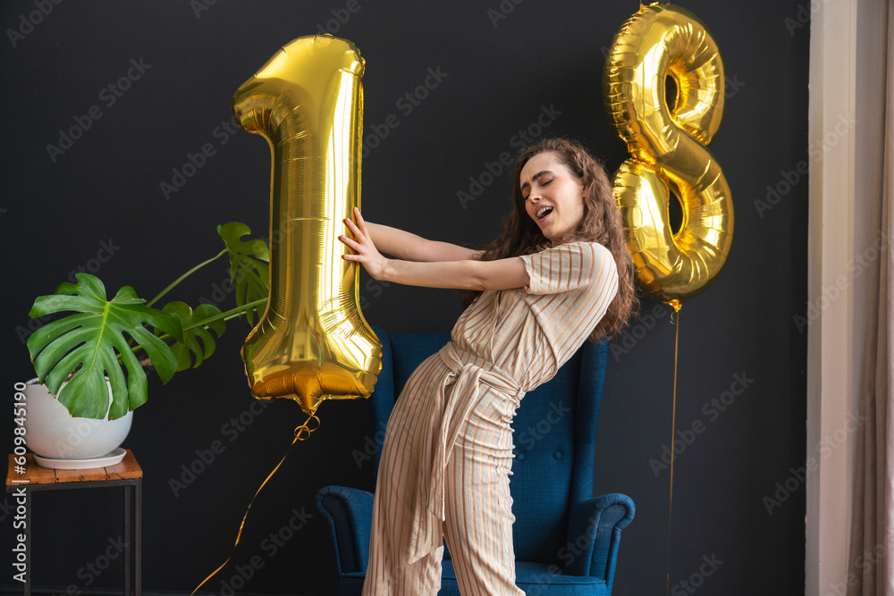 © Westend61 - Playful young woman holding number 1 helium balloon at home