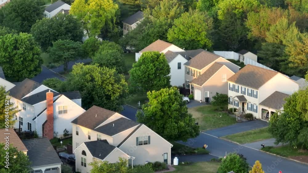 Neighborhood in American suburbs. Aerial view of houses with evening sunlight. Long aerial zoom.