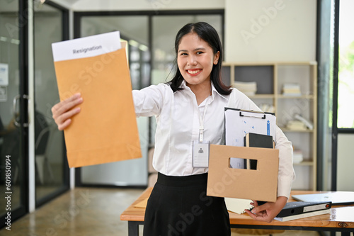 Excited Asian female office worker shows her resignation letter to the camera