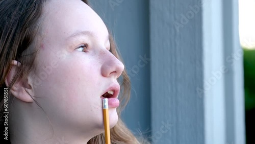 adolescence think dream miss close-up face of teenage girl taking pencil in mouth to think thinking street girl young woman draws does homework photo