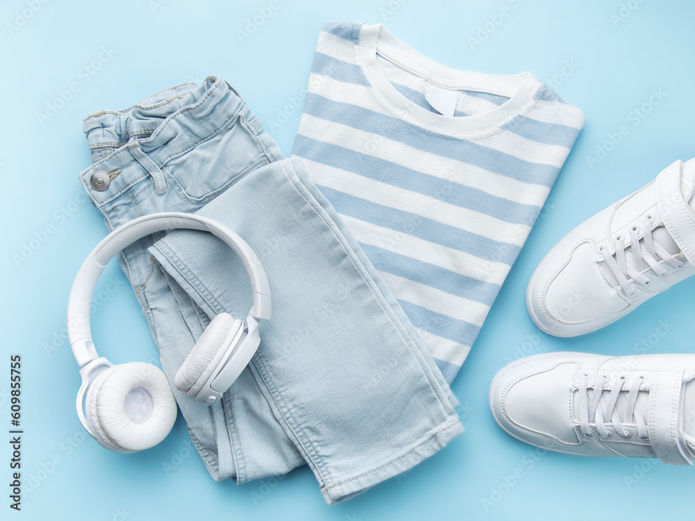 Child's t-shirt, shoes and headphones on blue backgrund
