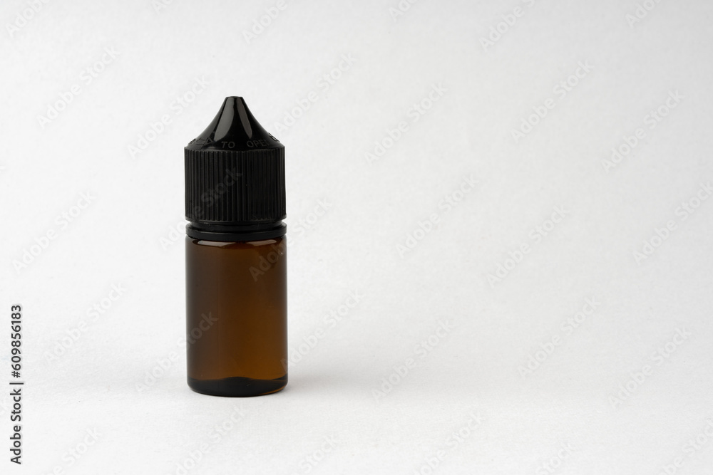 Small black glass dropper bottle front view on gray background Small black glass dropper bottle front view on gray background
