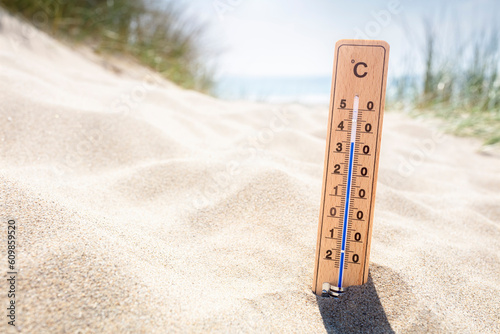 Thermometer in sand on the beach showing high temperature background photo