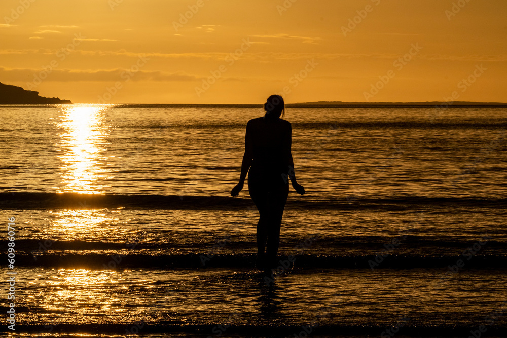 Silhouette of female swimmer going into the Atlantic ocean in Ireland
