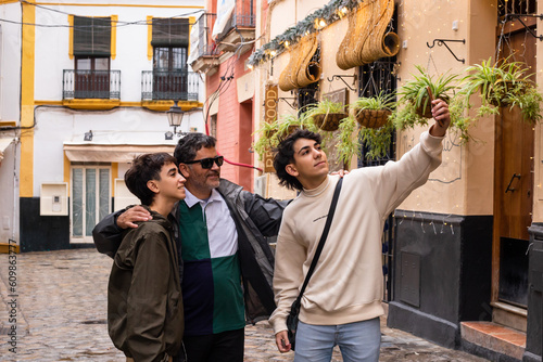 family of two brothers and father take a selfie on a trip through the streets of Seville, Spain
