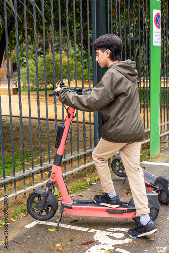fifteen-year-old teenager, unlocks an electric scooter through his cell phone, at a public scooter stop