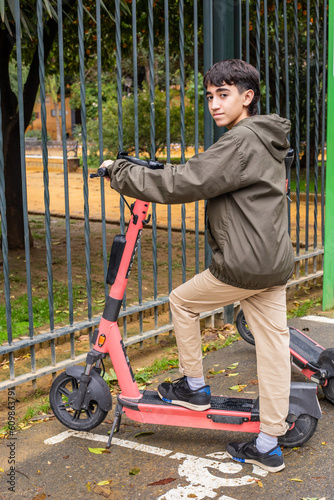 fifteen-year-old teenager, unlocks an electric scooter through his cell phone, at a public scooter stop