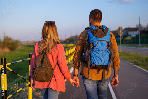 Adult couple is walking together by the road and holding hands.