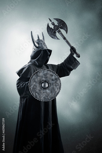 Warrior with horned helmet, double headed battle axe and round shield in the dark photo