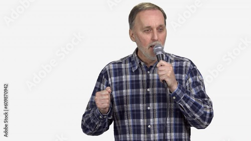 Handsome mature man is singing in microphone. Isolated on white. photo