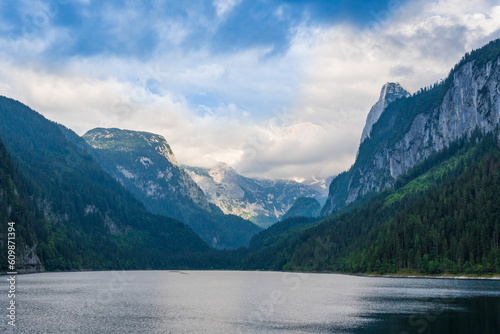 Beautiful landscape mountain forest lake view. Amazing summer cloudy scenery of Gosausee mountain lake and Dachstein mountain summit. Colorful scenery in Alps. Popular travel and hiking destination. © Uniqueton
