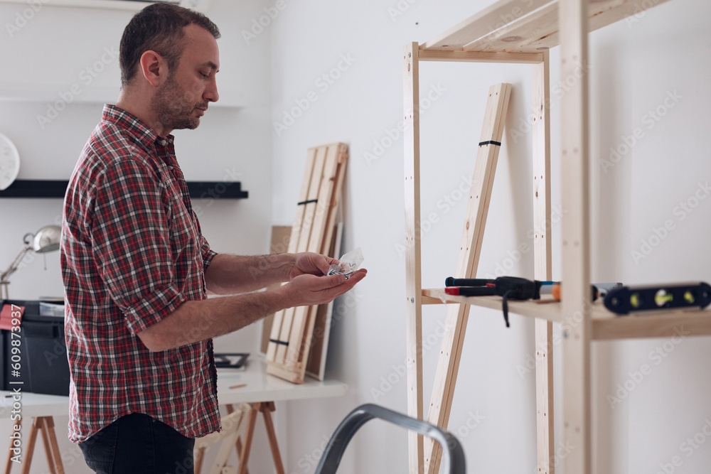 Man assembling new wooden shelf and furniture in the apartment. Man assembling new wooden shelf and furniture in the apartment.