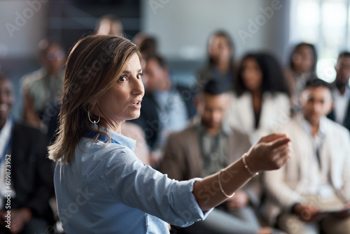 Presentation, training and coaching with a business woman talking to an audience during a workshop. Convention, speech and teaching with a female speaker giving a seminar to a group of employees photo