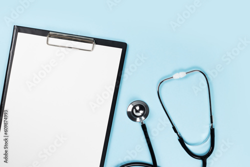 Blank clipboard with stethoscope on blue background photo