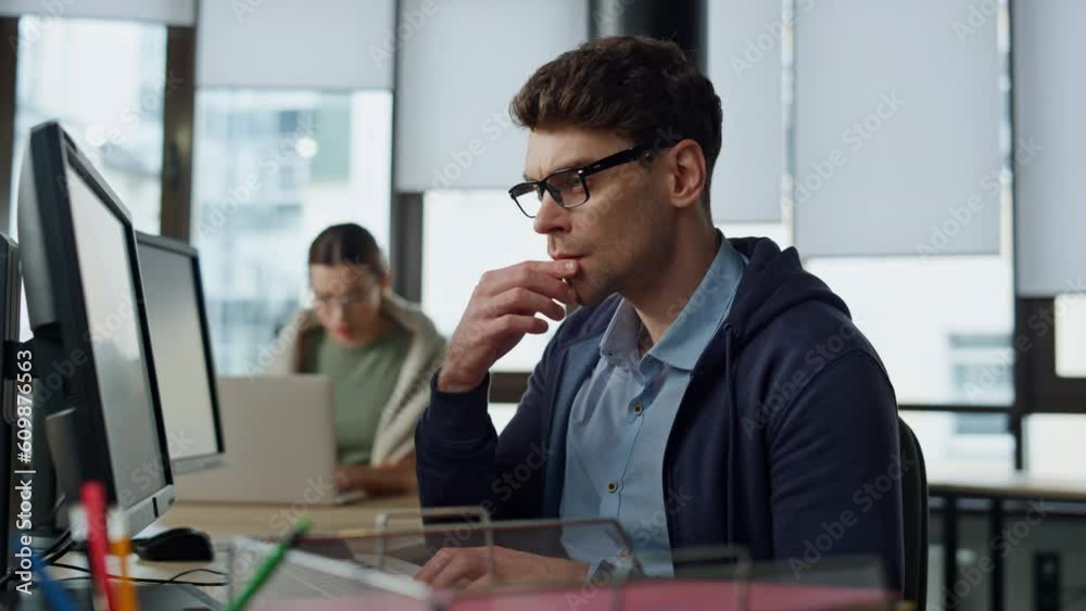 Thoughtful programmer looking computer at desk. Focused it man analysing code