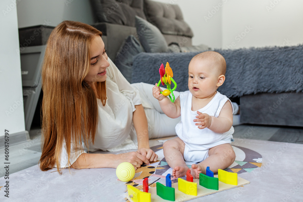 Mother and little daughter play educational games on rug in room. Mother and little daughter play educational games on rug in room.