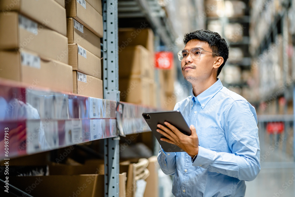 Businessman or supervisor uses a digital tablet to check the stock inventory in large warehouses, a Smart warehouse management system, supply chain and logistic network technology concept.. Businessman or supervisor uses a digital tablet to check the stock inventory in large warehouses, a Smart warehouse management system, supply chain and logistic network technology concept..