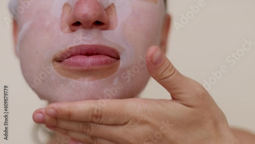 millennial woman doing face procedures,applying under eye patches,vitamin c serum or sheet facial mask.female girl with towel on head having fun,cover mouth with blanket or book.face through palms photo