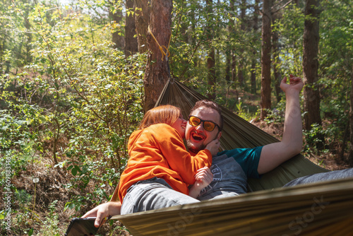 Couple man and woman having fun in a hammock, tickling and biting. They laugh and have a good mood, love. Outdoor recreation. Date. Selective focus.