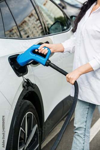 Young business woman refueling her electric car at a EV charging station. Concept of environmentally friendly vehicle. Electric car concept. Green travelling. © romeof