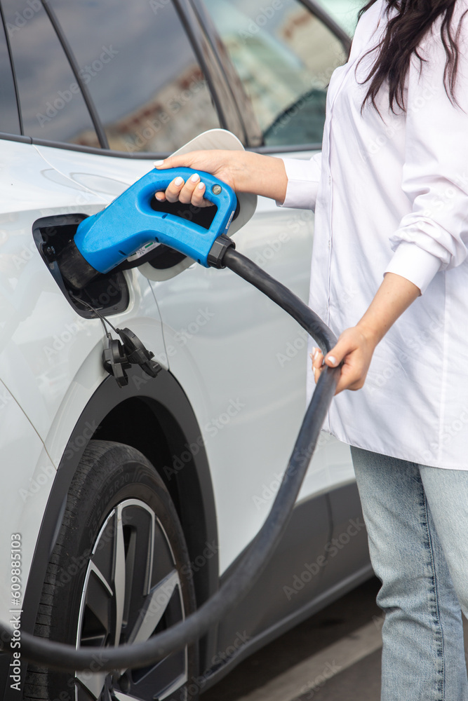 Young business woman refueling her electric car at a EV charging station. Concept of environmentally friendly vehicle. Electric car concept. Green travelling. Young business woman refueling her electric car at a EV charging station. Concept of environmentally friendly vehicle. Electric car concept. Green travelling.