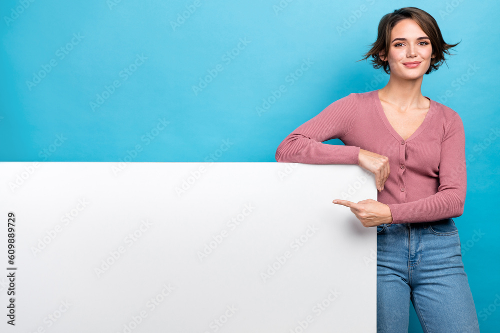 Photo of young attractive girl wear stylish clothes directing finger empty space whiteboard placard isolated on blue color background Photo of young attractive girl wear stylish clothes directing finger empty space whiteboard placard isolated on blue color background