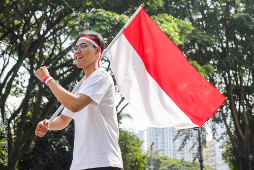 Portrait of young man holding Indonesian red and white flag, celebrating independence day.