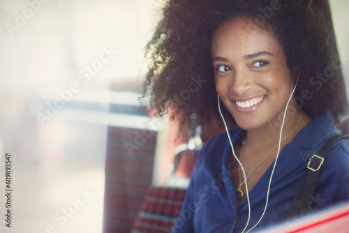 Smiling woman with afro listening to music with headphones on bus