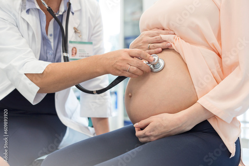 Doctor using stethoscope on pregnant patient‚Äôs stomach