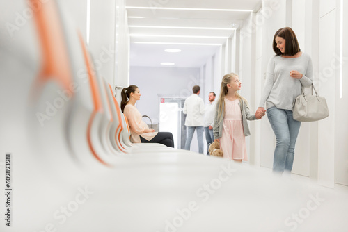 Photos Mother and daughter holding hands walking in hospital corridor