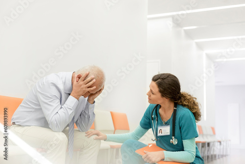 Φωτογραφία Nurse consoling upset man in clinic corridor