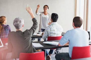 Teacher calling on student with hraised in adult education classroom