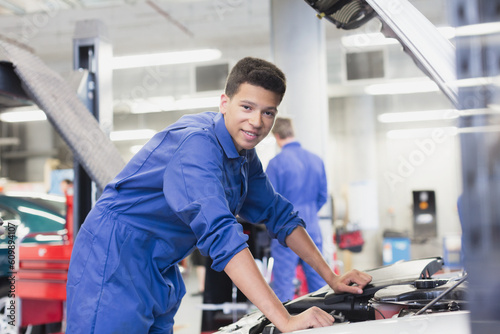 Portrait confident mechanic leaning over car engine in auto repair shop