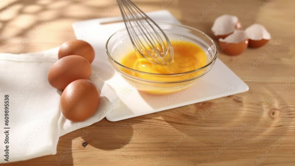 Whisking eggs. Man whisking raw eggs in a bowl. Breakfast preparation. Rustic style. Sunny day. Smooth camera movement. Close up. 4k footage. Whisking eggs. Man whisking raw eggs in a bowl. Breakfast preparation. Rustic style. Sunny day. Smooth camera movement. Close up. 4k footage.