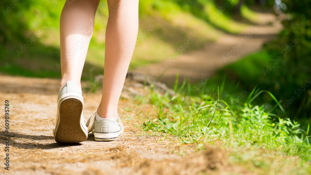 Legs of a girl walking along a path in the forest. Image with selective focus