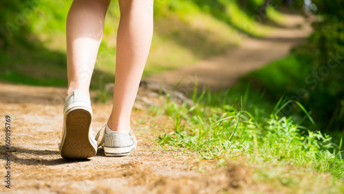 Legs of a girl walking along a path in the forest. Image with selective focus © SEA_Ekaterina
