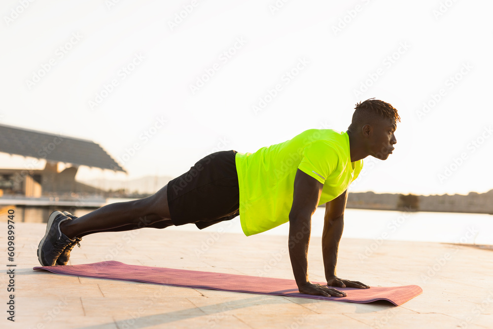 Naklejka premium Fitness training outdoors. Handsome African man doing exercises outside. Muscular man training.