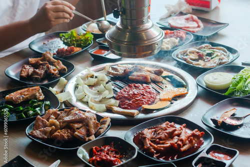 Korea BBQ style restaurant. Asian  traditional pickle vegetable ingredients on table with people grilling background.