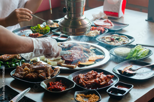 Korea BBQ style restaurant. Asian  traditional pickle vegetable ingredients on table with people grilling background.